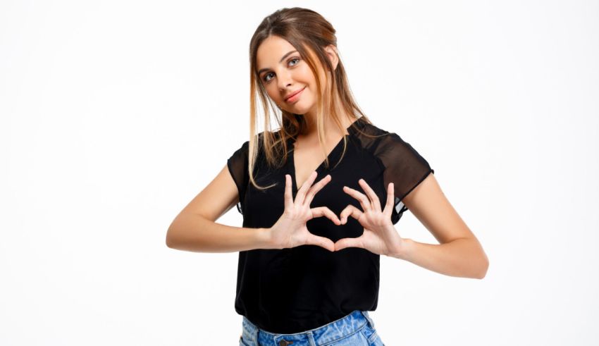 A young woman is making a heart sign with her hands.