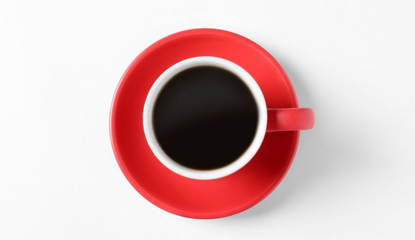 A cup of coffee on a red saucer on a white background.