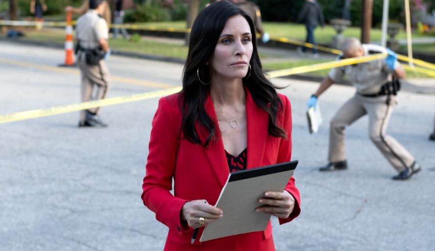 A woman in a red suit holding a tablet.