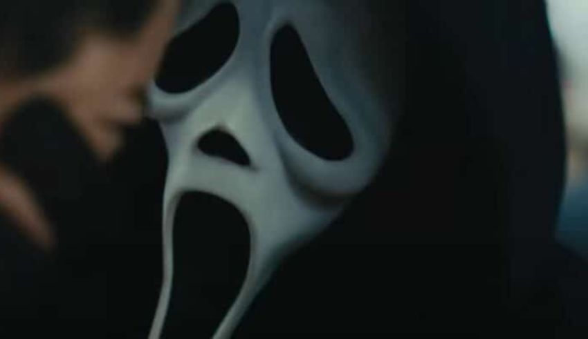 A woman wearing a scream mask is kissing a man.