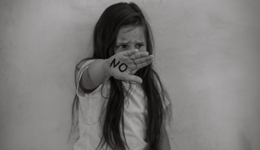 A black and white photo of a girl with the word no written on her hand.