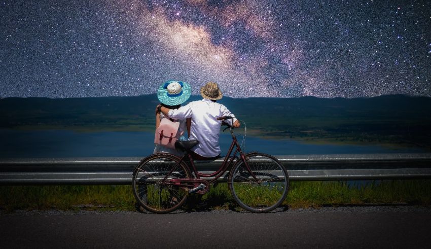 A couple on a bicycle looking at the milky way.