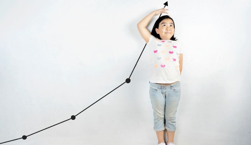 A little girl is holding up a black line on a white wall.