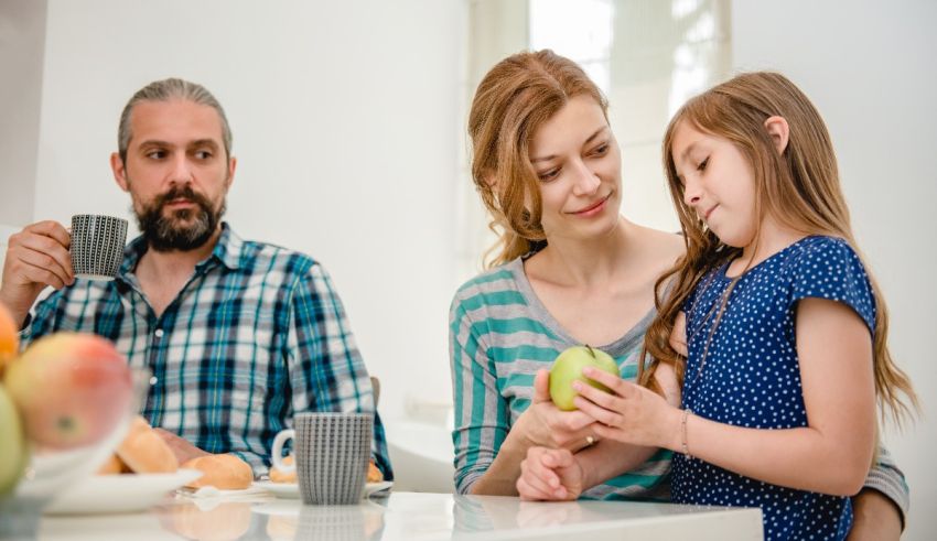 A family is sitting at the table and eating an apple.
