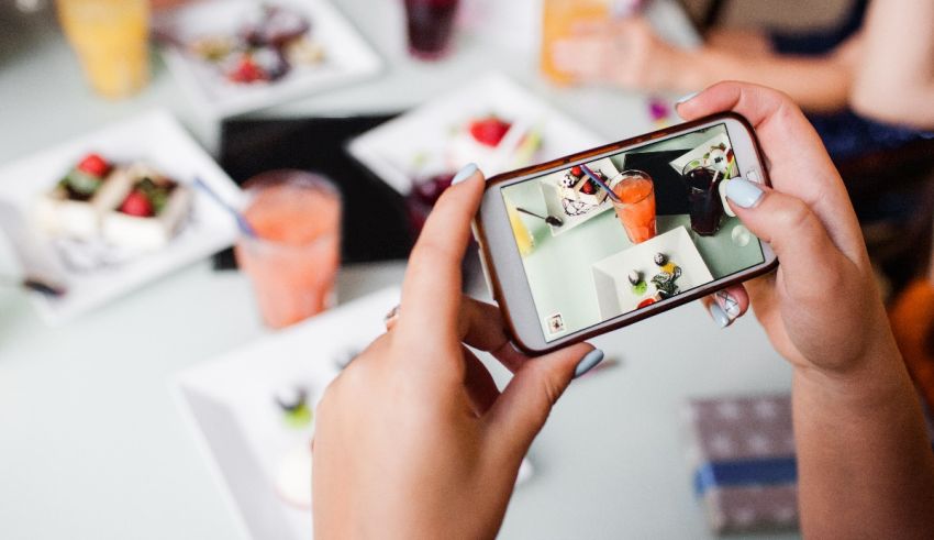 A person taking a photo of a table full of food.