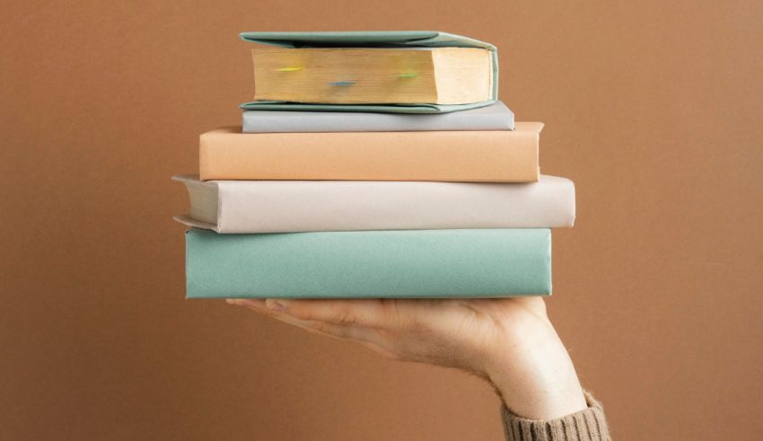 A hand holding a stack of books on a brown background.