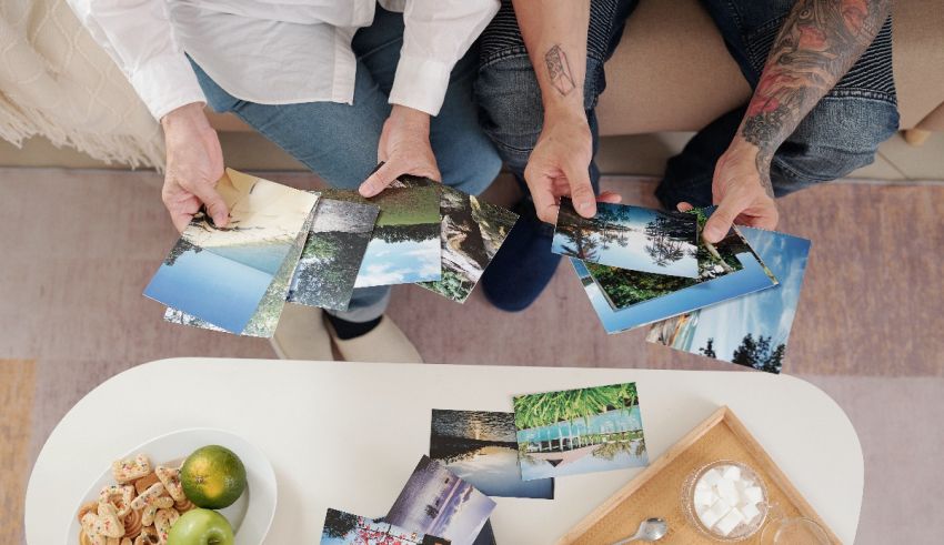 Two people holding photos on a coffee table.