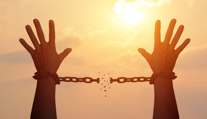 A woman's hands are chained to a chain with the sun behind them.