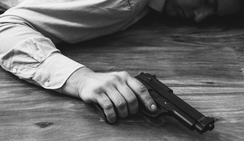 A man laying on a wooden table with a gun.