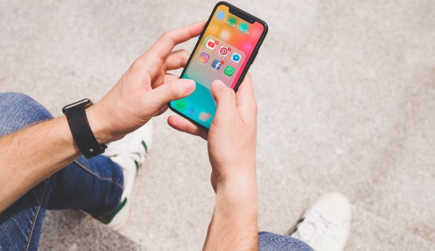 A person holding an iphone x on the ground.