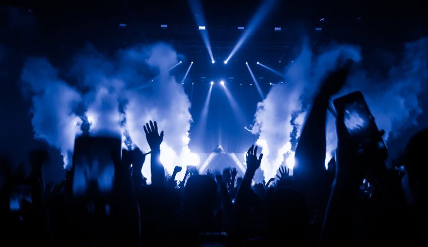 A crowd of people at a concert with smoke coming out of their hands.