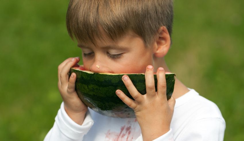 A young boy eating a piece of watermelon.