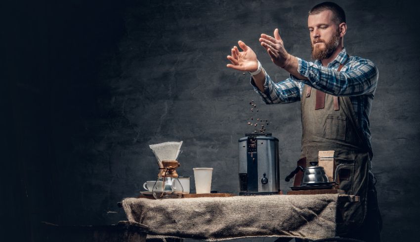 A man in an apron is pouring coffee into a coffee maker.