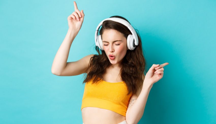 A young woman wearing headphones and dancing on a blue background.