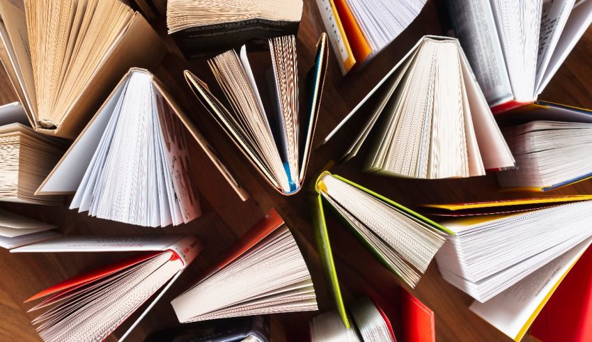 A group of books arranged in a circle on a wooden table.