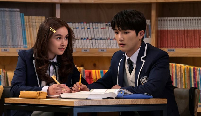 A couple in school uniforms sitting at a desk in a library.