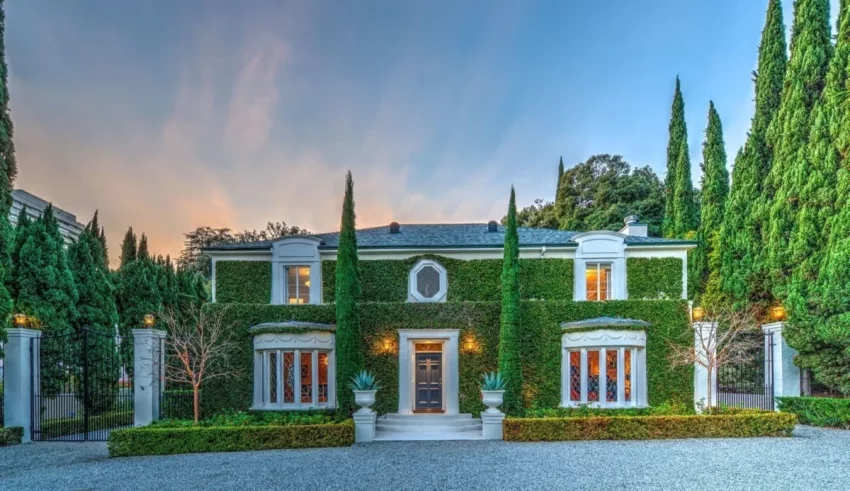 A mansion with cypress trees and a driveway.