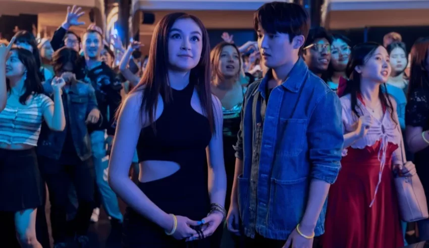 Two people standing in front of a crowd at a party.