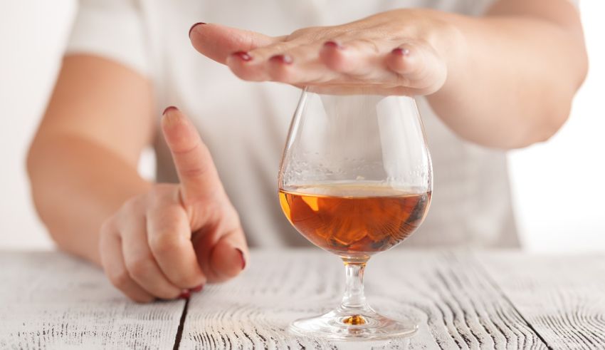 A woman's hand reaching into a glass of wine.