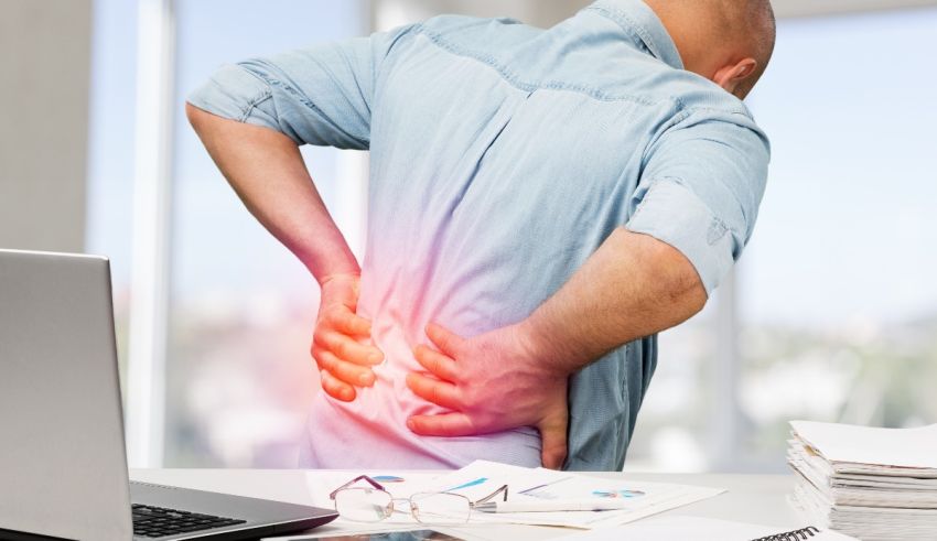 A man with a back pain in front of a laptop.