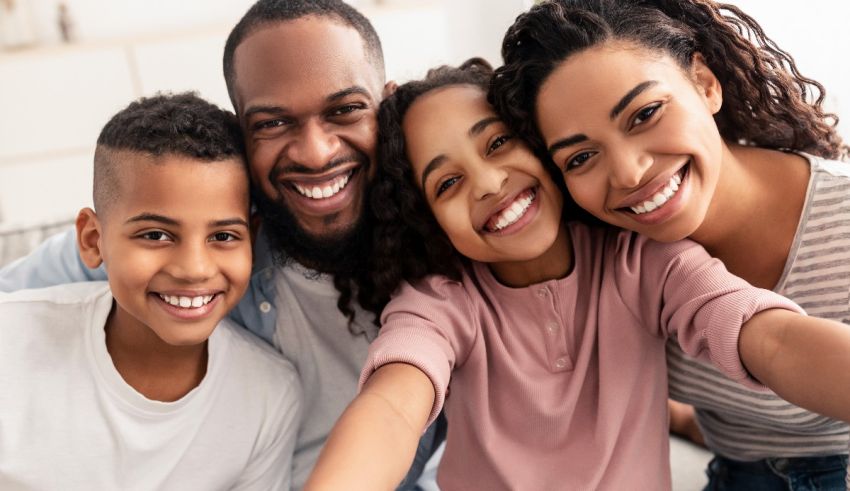 A family is taking a selfie while sitting on the couch.