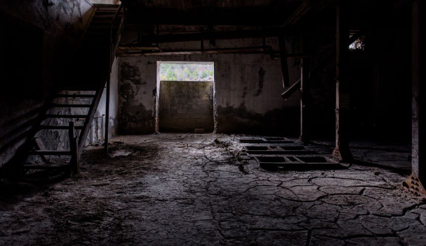A room in an abandoned building with stairs and a window.
