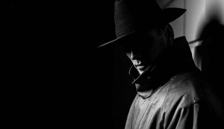 A man in a hat is standing in a dark room.