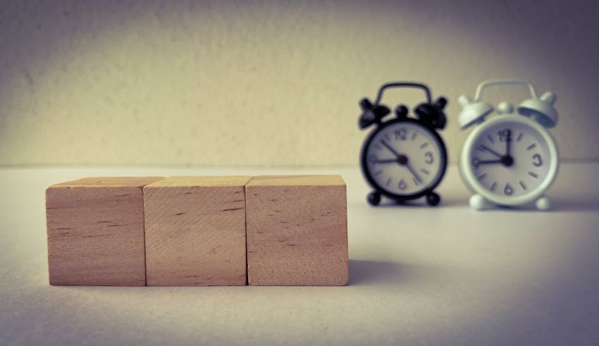 Two wooden cubes next to an alarm clock.