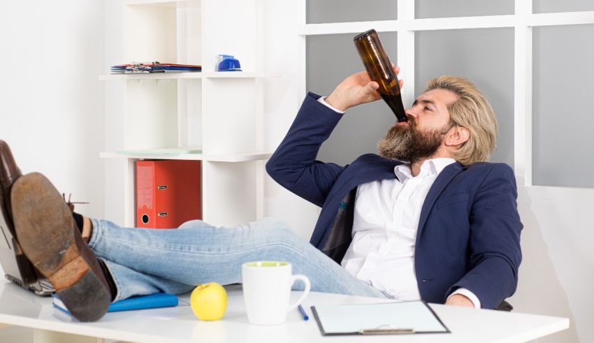 A man sitting at his desk drinking a beer.