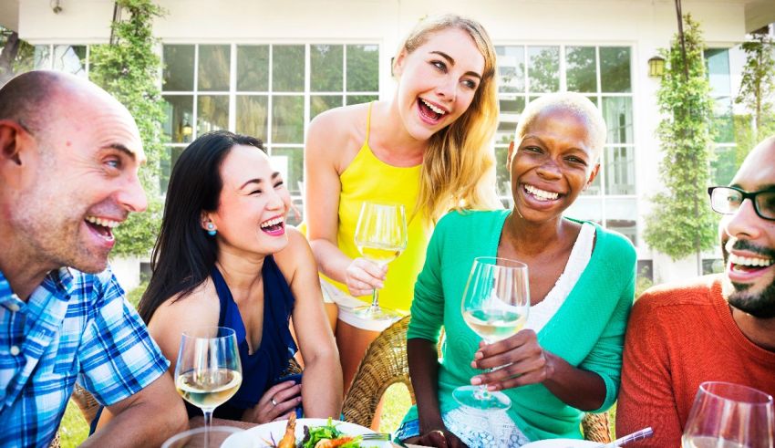 A group of friends laughing at a table with wine glasses.