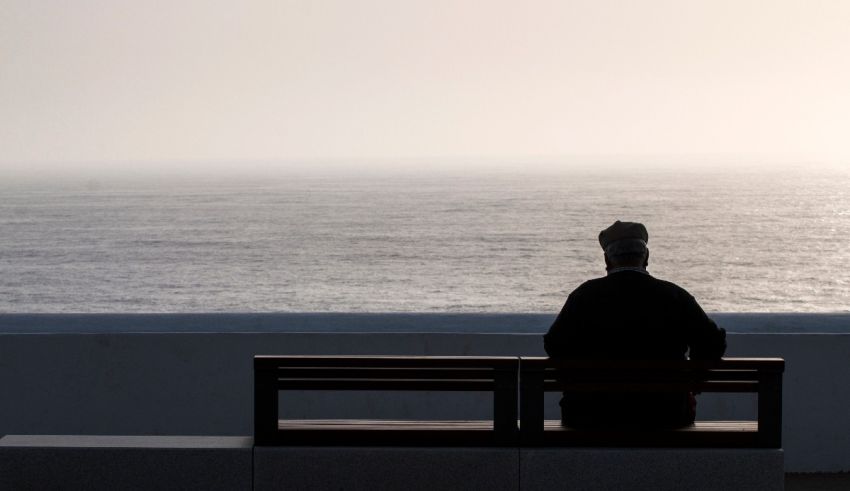 A person sitting on a bench looking at the ocean.