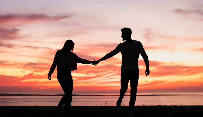 Silhouette of couple holding hands at sunset.