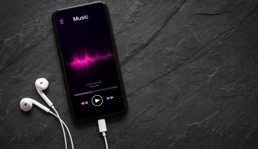 A smartphone with music playing on it and earphones plugged in.
