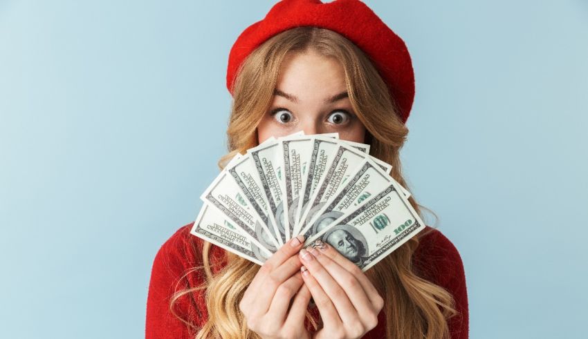 A woman with a red hat covering her face with dollar bills.