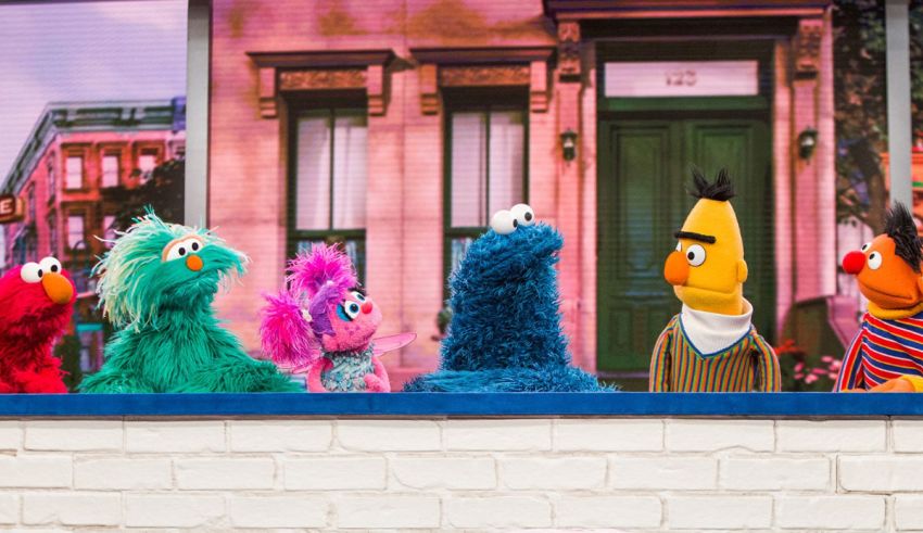 A group of sesame street characters standing in front of a brick wall.
