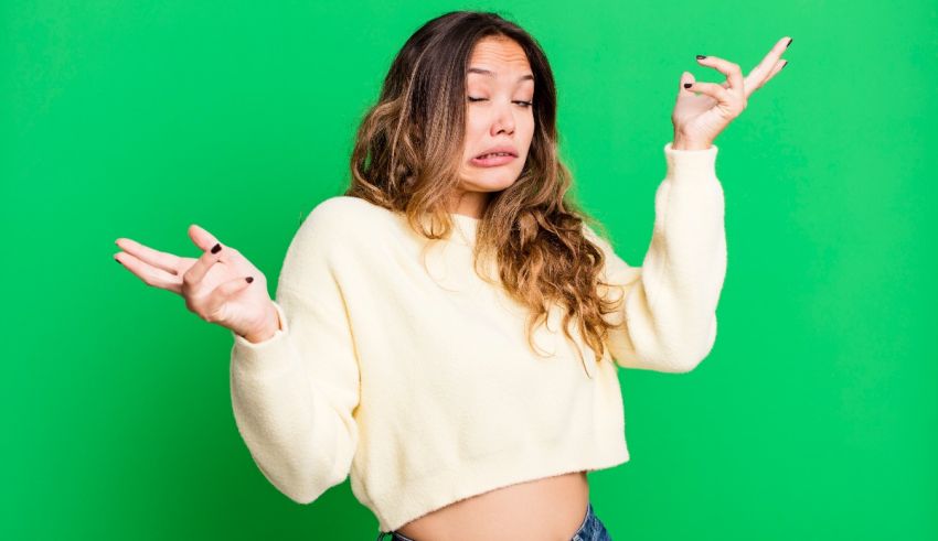 A young asian woman making a gesture against a green background.