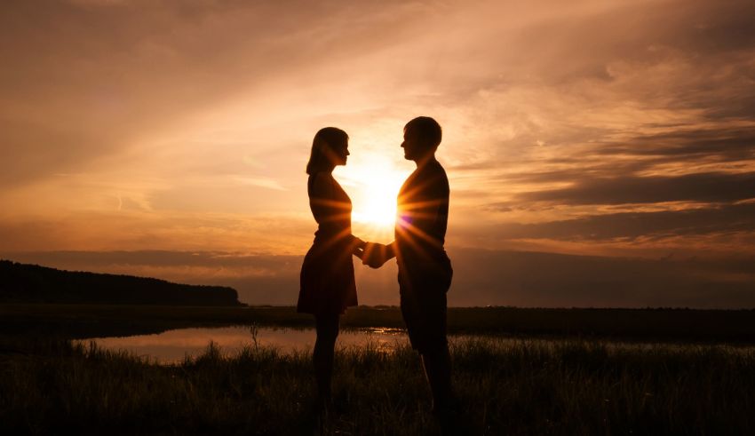 Silhouette of a couple holding hands at sunset.