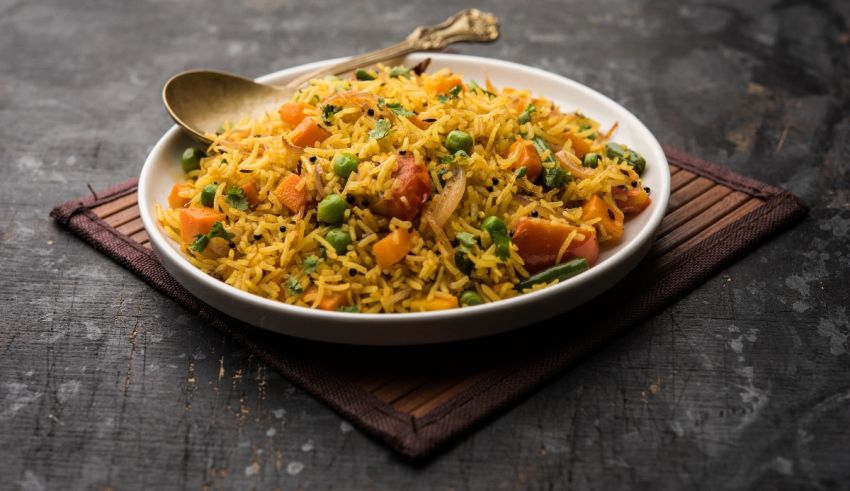 A bowl of rice with peas and carrots.