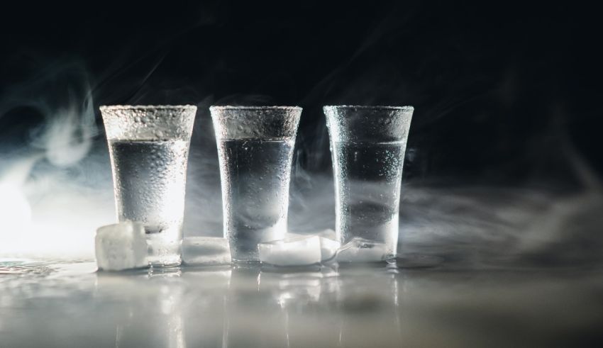 Three glasses of water with ice cubes on a black background.