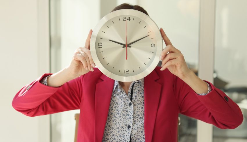 A woman is holding a clock in front of her face.