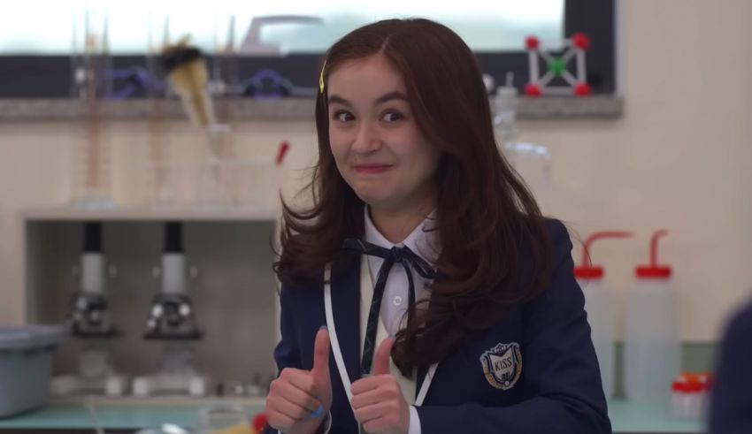 A girl in a school uniform giving a thumbs up.