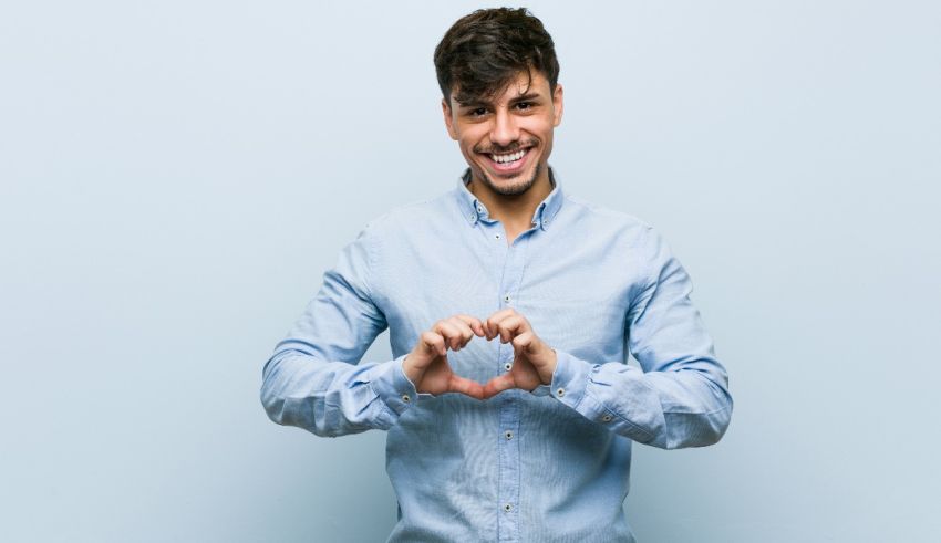A young man making a heart shape with his hands.