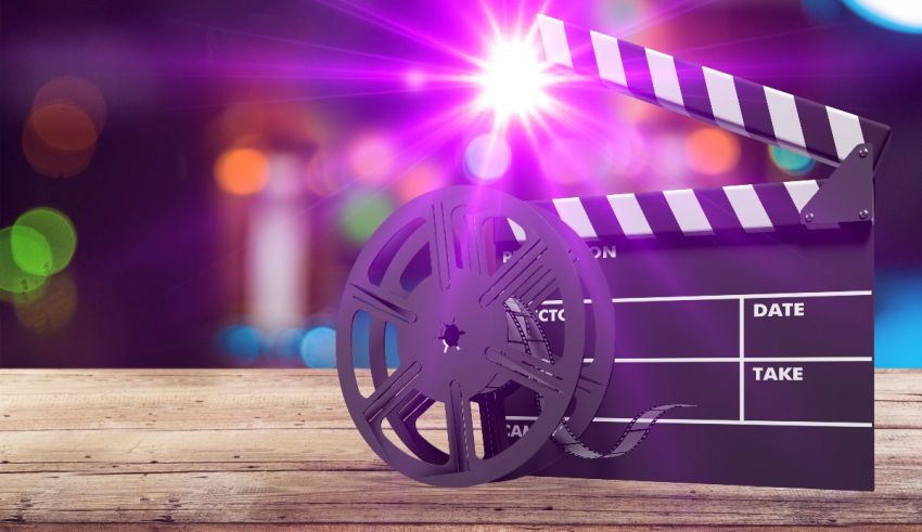 A clapper board and film reel on a wooden table.