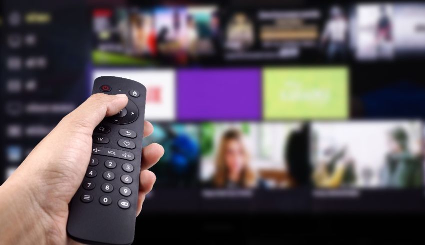 A hand holding a remote control in front of a tv screen.