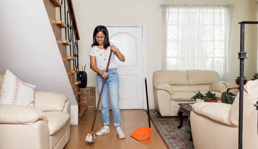 A woman cleaning her home with a mop and broom.