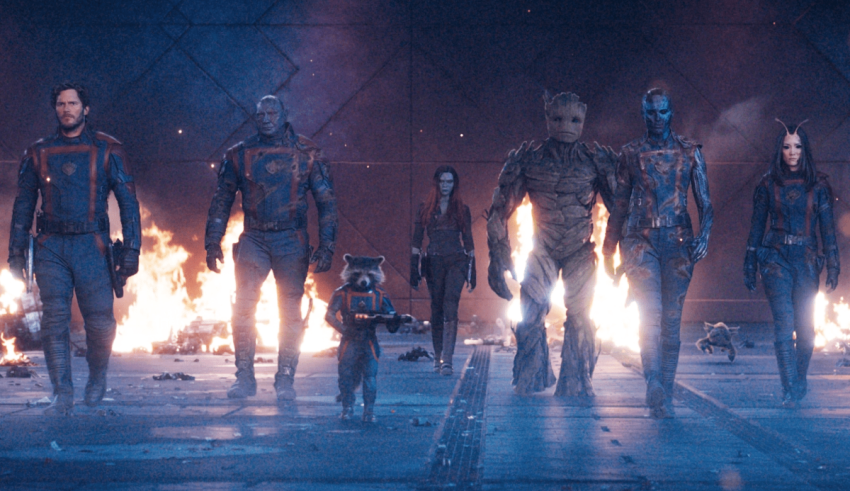 A group of guardians of the galaxy standing in front of a fire.