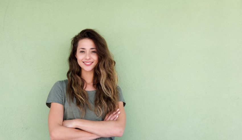 A smiling young woman standing against a green wall.