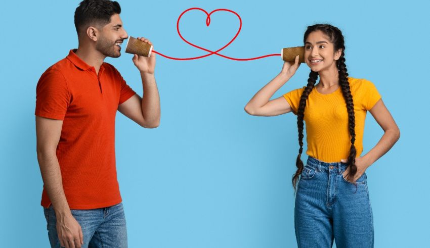 A man and a woman talking on a phone while making a heart shape.