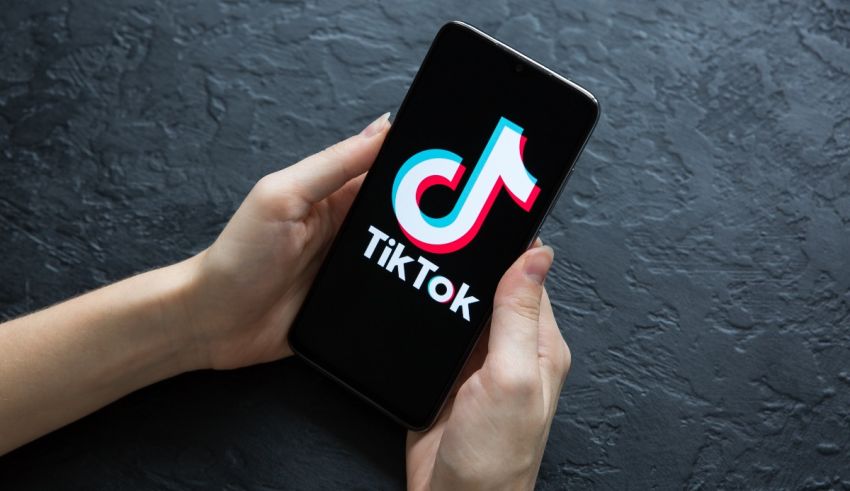 A person holding a phone with the tiktor logo on it.